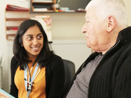 Health worker smiling and talking with an older patient during an appointment. Health worker smiling and talking with an older patient during an appointment.
