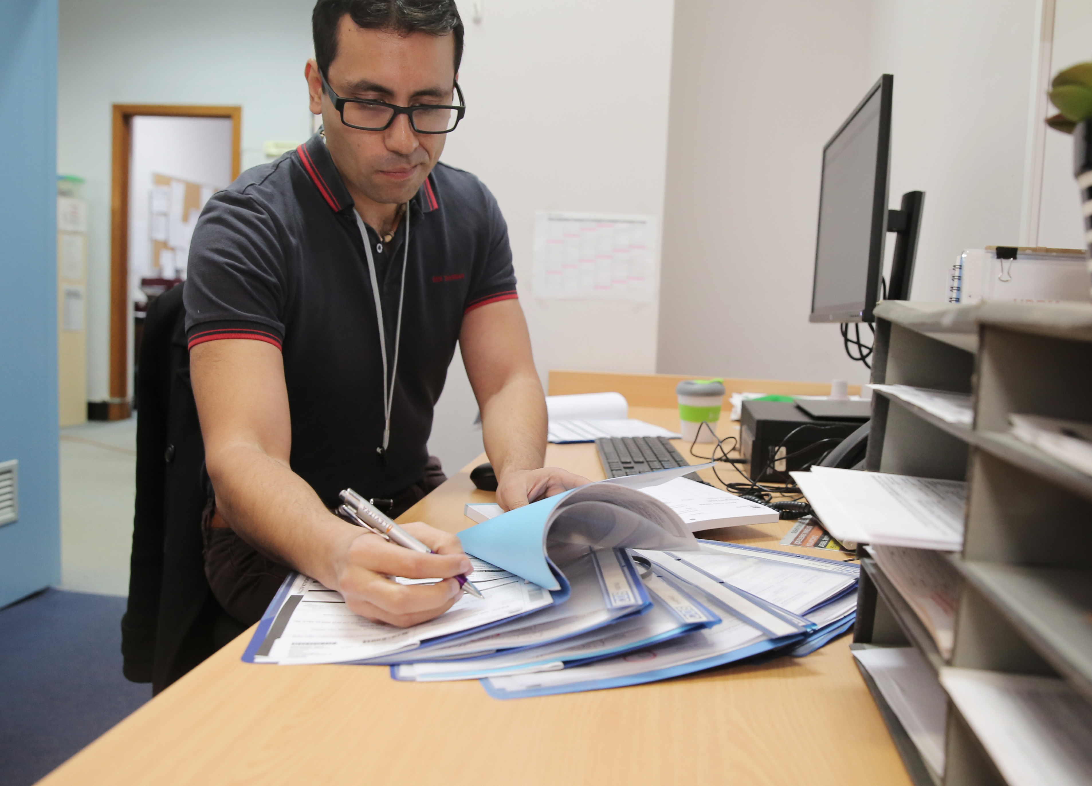 Health worker at a desk completing paperwork and reviewing patient forms.